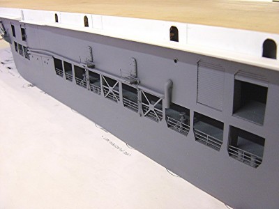 A close up view of portside. The sides of the ship were fabricated from .020 styrene. The openings were then cut out and details added such the railings and cross braces. These side pieces were then attached to the hull. I then added all the piping, platforms etc. before a primer coat was added. Noto the gallery deck taking shape, still in raw white styrene.
