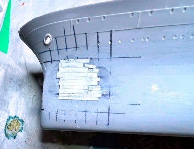 Strips of styrene filling the dent.  The strips at the edges are thinner than in the middle, and I added a second layer near the center.  After this picture was taken, it was all buried under a layer of putty.