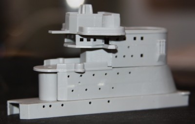 Parts are dry-fitted. I removed the large "bands" that wrapped around the structure. I'm not sure what they were meant to be, but I certainly can't find any in the photos I've seen. So, they're GONE! I'm debating whether or not to replace the "crown" on top that's supposed to represent the top of the quadripod legs. Again, photos show that this was not solid. I've also sanded down all the tiny raised edges that were on all of the decks and platforms. I guess these were "railings". I'll be putting GMM railings on the ship. I've done a few more things, like opening the portholes and cutting openings for access to the "wings" below the director platforms.