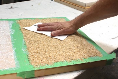 I'm using a paper towel to press the oat bran into the gel medium.  I want it to stick.  Once this surface is dry, I will brush a layer of regular acrylic medium on top of this to make things more solid and glued down.