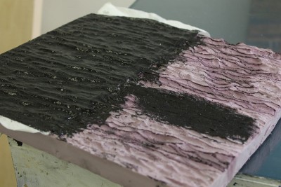 Here I have used a dremel tool and a steel brush bit to create a wave texture.  I used spray adhesive and covered it with one single coating of paper towel.  Right is the raw carved foam, left is the paper towel coating with paint.